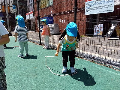 戸外ではボールや縄跳びで身体を動かして遊びました。縄跳びは保育士に縄を揺らしてもらい、順番に１０回ずつ飛びました。一回飛んだ後にまたすぐ飛ぶリズム感を知ってもらう為に「縄が来るよ～！」と伝えることで飛んだ後も身体の向きを変えたり体勢を変えたりして準備することが出来ていました。<br />
ボール遊びではボールの跳ね返りを楽しんだり、キャッチすることを繰り返して遊んでいました。保育士が投げる際に「１，２，３」と掛け声をして投げ、「３」で<br />
ボールを掴む感覚を伝えながら一緒に遊んでいます。